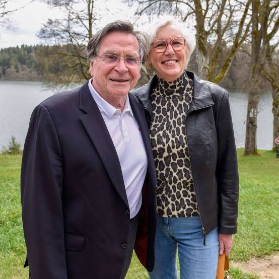 Anita Schlierf und Elmar Wepper stehen lächelnd nebeneinander an einem See.