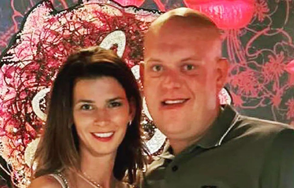Daphne Govers und Michael van Gerwen lächeln gemeinsam vor einer pinken Wanddekoration
