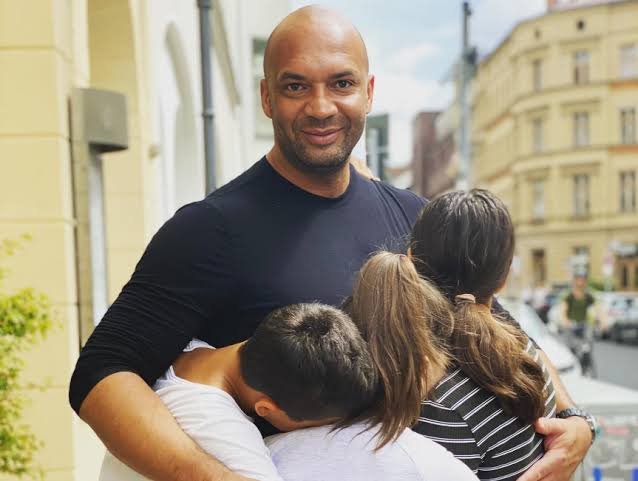 Detlef D! Soost umarmt lächelnd drei Kinder auf einer Straße in Berlin