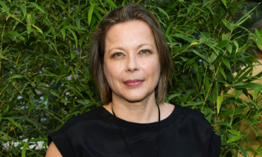 Tanja George, Tochter von Schauspieler Götz George, mit schulterlangen Haaren und schwarzem Oberteil vor grünen Bambusblättern